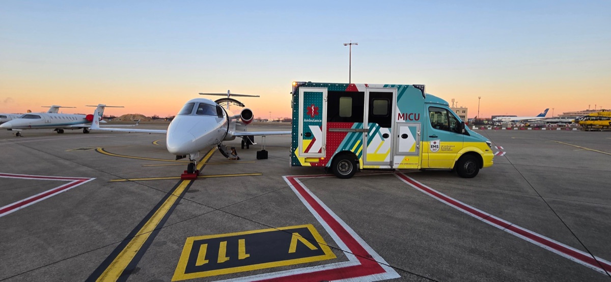 EMS mobile intensive care ambulance parked beside a Learjet air ambulance on the apron at dusk